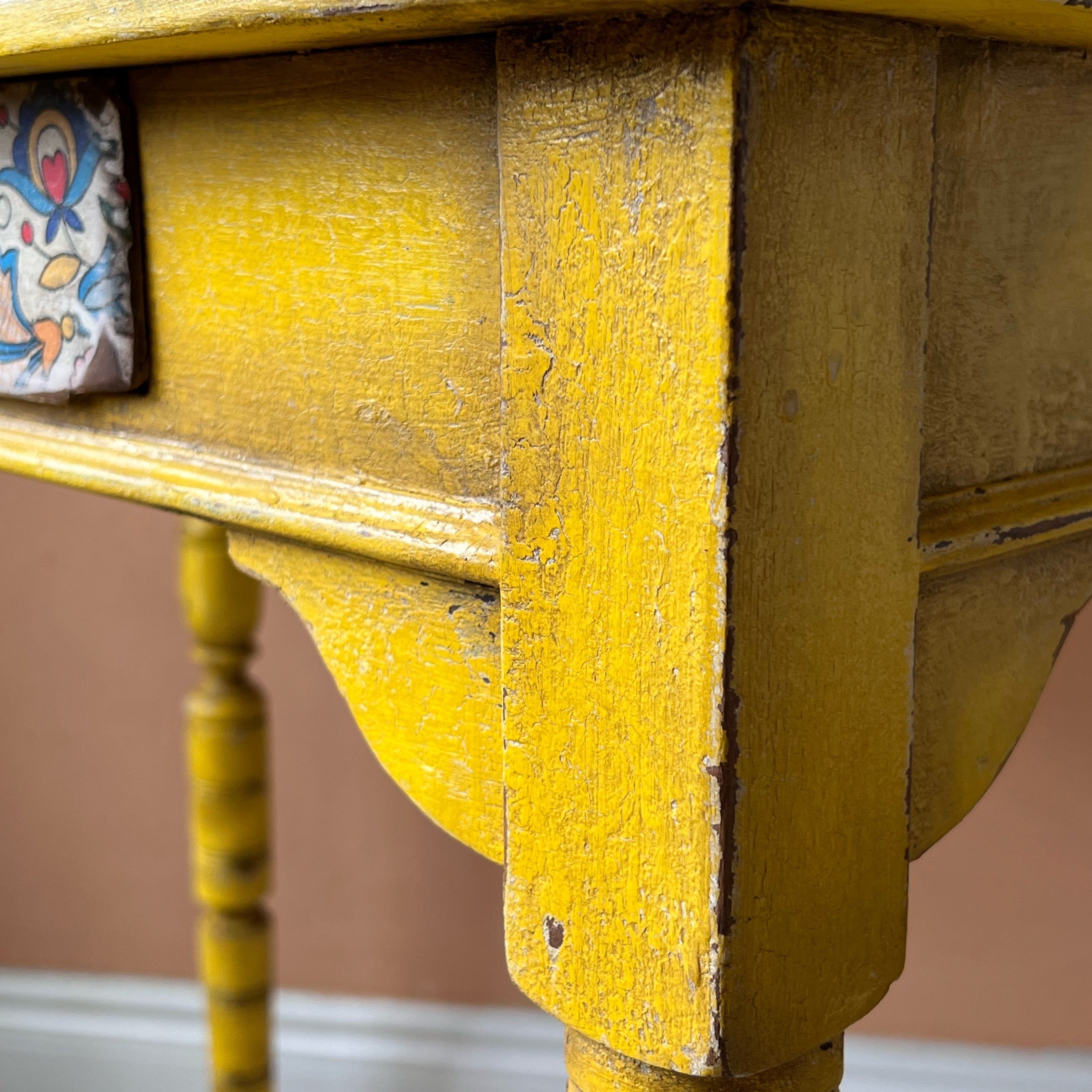 Rustic yellow console table with folk art detail